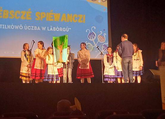 uczniowie w strojach kaszubskich stoją na scenie