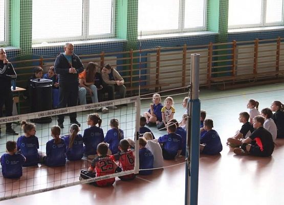 zawodnicy siedzą na podłodze i słuchają wskazówek