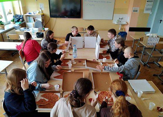 uczniowie jedzą pizzę