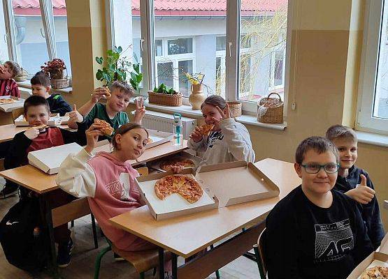 uczniowie jedzą pizzę