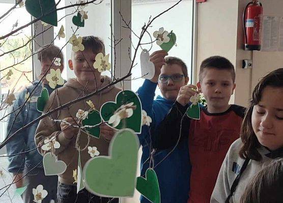 uczniowie zawieszają serca na drzewie