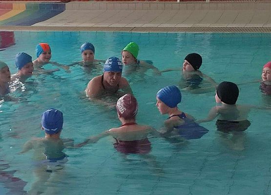 uczniowie z trenerem podczas zajęć na basenie