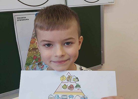 chłopiec prezentuje swoją pracę plastyczną