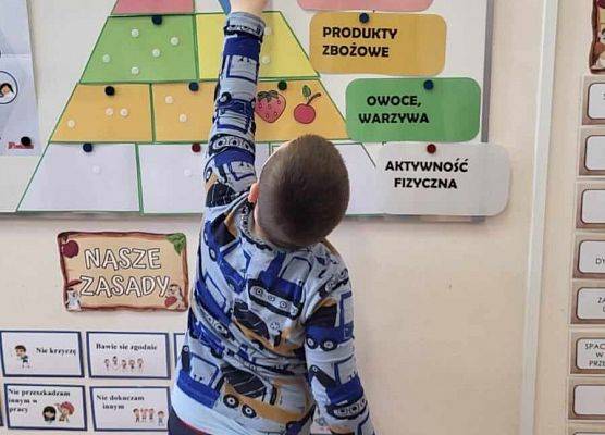 chłopiec przykleja obrazek na tablicy