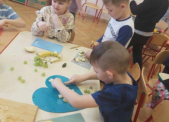 dzieci przygotowują sałatkę owocową