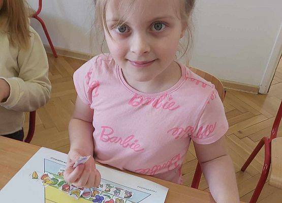 dziewczynka układa produkty na piramidzie zdrowego żywienia