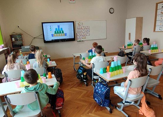 uczniowie układają wieżę z kubeczków i obliczają wyniki dodawania