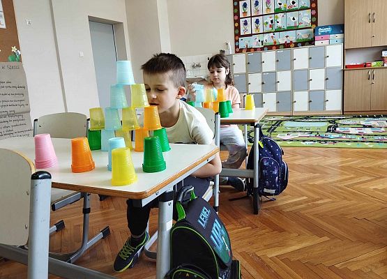 uczniowie układają wieżę z kubeczków i obliczają wyniki dodawania