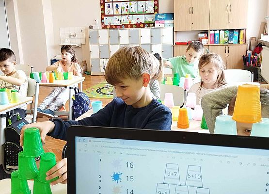 uczniowie układają wieżę z kubeczków i obliczają wyniki dodawania