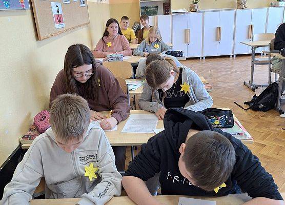 uczniowie siedzą przy stolikach