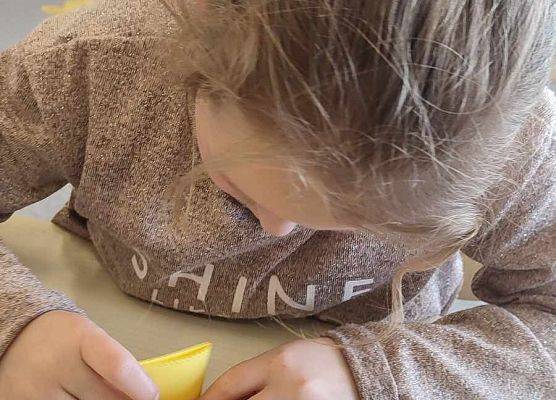 dziewczynka robi żonkila z papieru