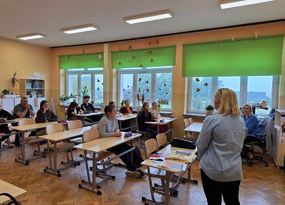 uczniowie siedzą w ławkach i oglądają prezentację