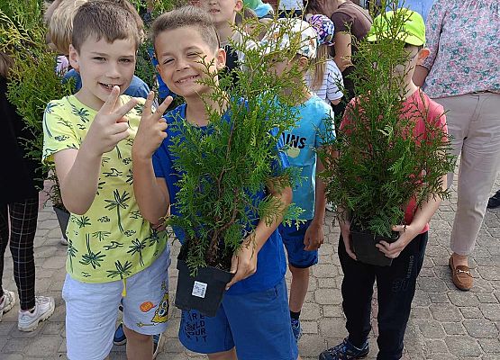 uczniowie trzymają sadzonki drzewek