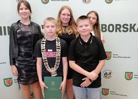 uczniowie pozują do zdjęcia na ściance z napisami Gmina Nowa Wieś Lęborska
