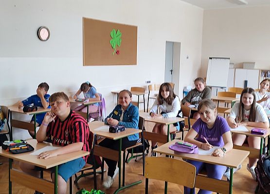 uczniowie siedzą w ławkach podczas zajęć