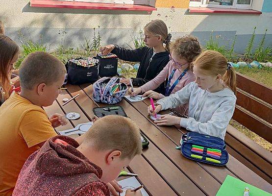 uczniowie uczą się przed budynkiem szkoły