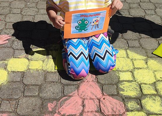 dziewczynka rysuje kredą na chodniku