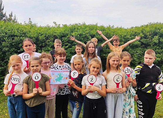 uczniowie trzymają znaczki z literkami