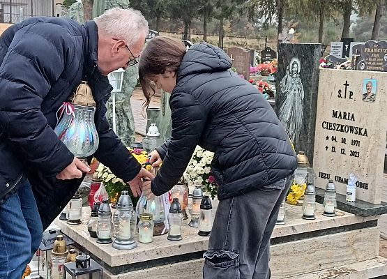 dyrektor z uczennicą ustawiają znicze