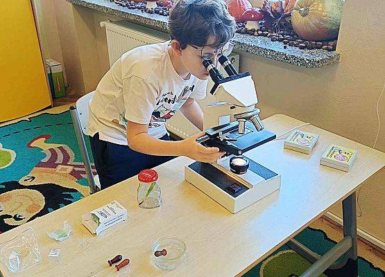 uczeń patrzy przez mikroskop