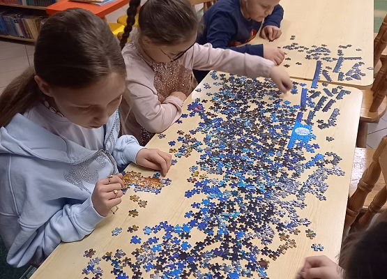 uczniowie układają puzzle
