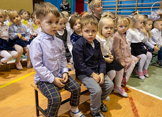 dzieci siedzą na ławeczkach