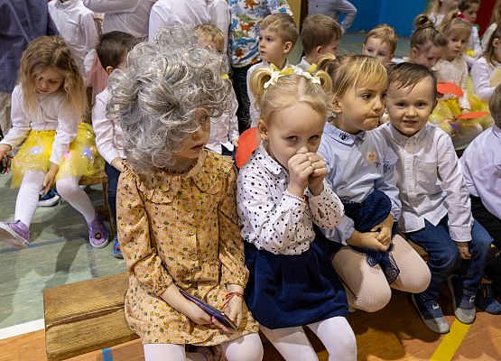 dzieci siedzą na ławeczkach