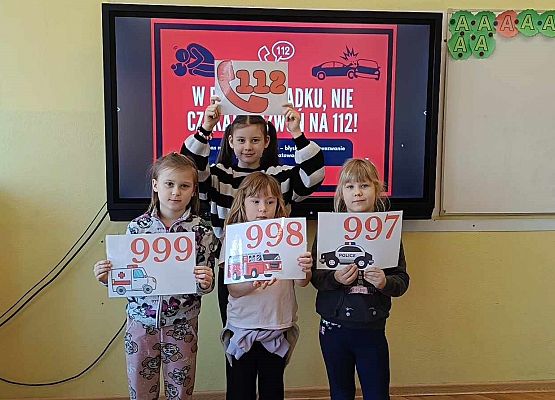 uczniowie prezentują na kartach numery alarmowe