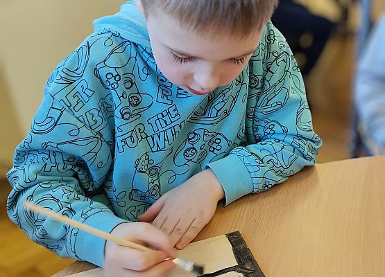 chłopiec maluje na drewnie