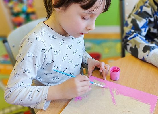 dziewczynka maluje na drewnie