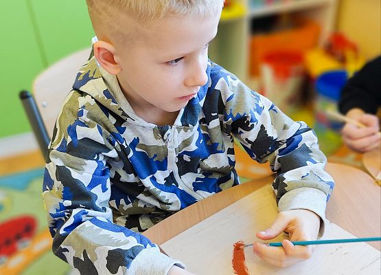 chłopiec maluje na drewnie