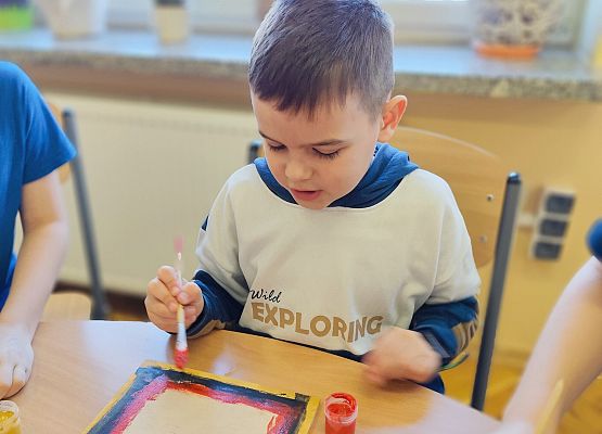 chłopiec maluje na drewnie