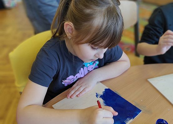 dziewczynka maluje na drewnie