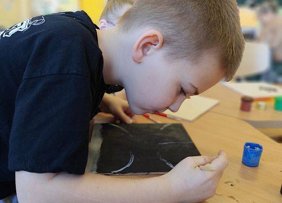 chłopiec maluje na drewnie