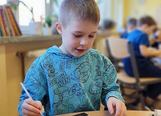 chłopiec maluje na drewnie