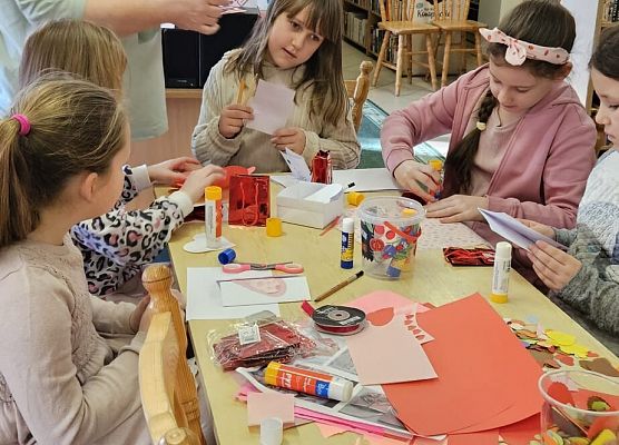 nauczycielka podpowiada dzieciom, jak wykonać kartki walentynkowe