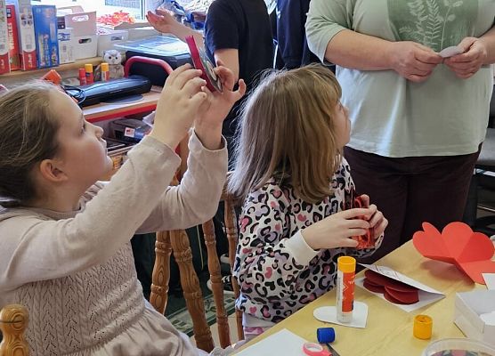 nauczycielka podpowiada dzieciom, jak wykonać kartki walentynkowe