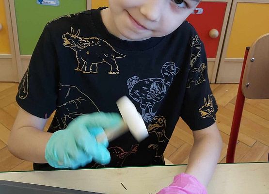 Chłopiec rozbija młotkiem jajko dinozaura