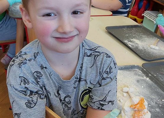 Chłopiec pokazuje fragment dinozaura ukrytego w gipsowym jajku