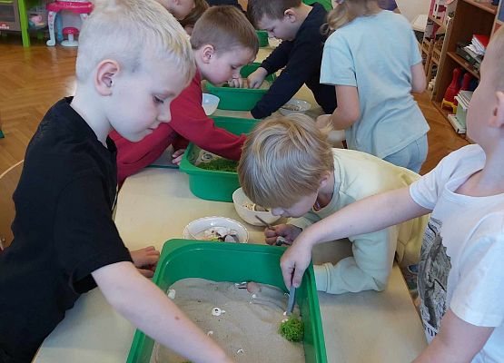 Dzieci szukają w piasku ukryte przedmioty