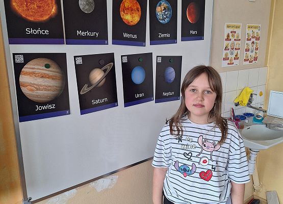 uczennica stoi przy planszach z planetami