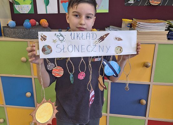 chłopiec trzyma kartę z napisem układ słoneczny