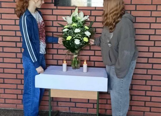 uczennice ustawiają znicze przy tablicy pamięci Jana Pawła II