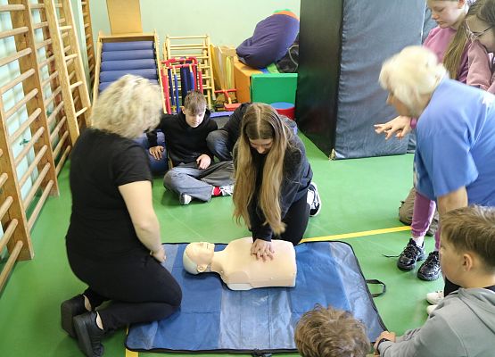 uczniowie wykonują zadanie z pierwszej pomocy przedmedycznej w obecności nauczycielki