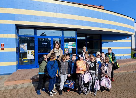 uczniowie z nauczycielką przed budynkiem pływalni