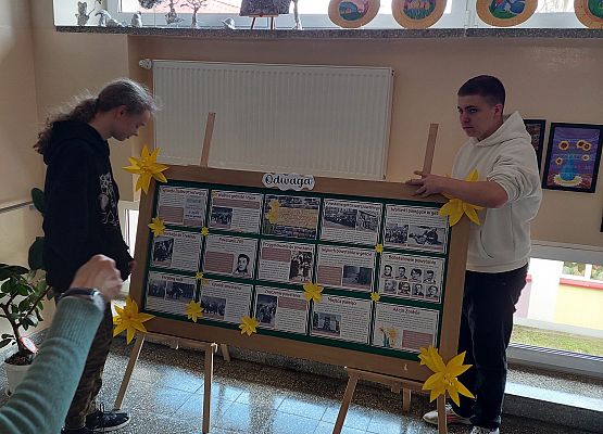 chłopcy wywieszają na tablicy informacje