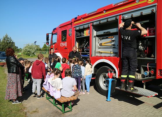 strażacy przed budynkiem szkoły pokazują wóz strażacki