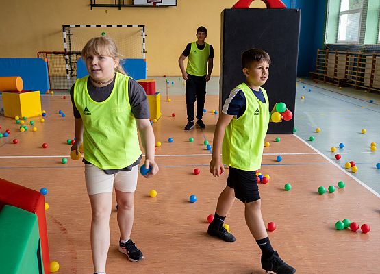 uczniowie w sali gimnastycznej  grają w paintballa