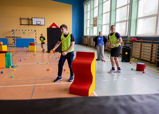 uczniowie w sali gimnastycznej  grają w paintballa