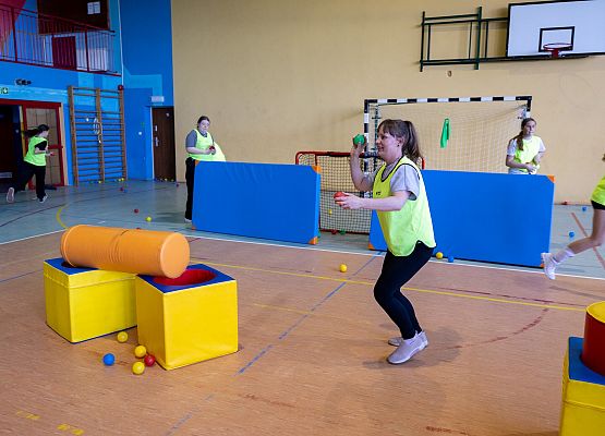 uczniowie w sali gimnastycznej  grają w paintballa